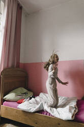 Happy girl having fun jumping on bed in bedroom - JOSEF17051