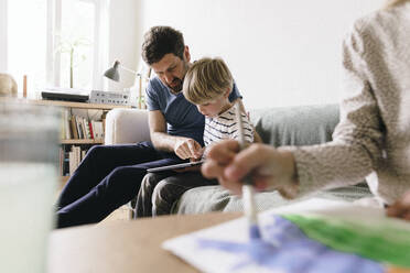 Father explaining son sitting with tablet PC at home - JOSEF17075