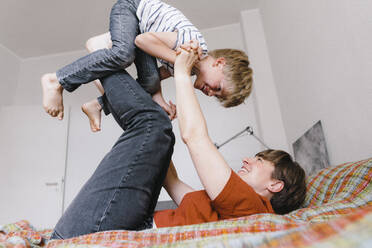 Son playing with mother lying on bed at home - JOSEF17081