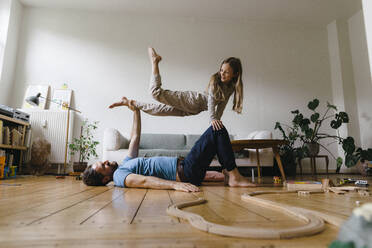 Mature man balancing girl on hand and knees in living room - JOSEF17084