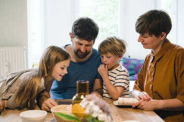 Familie sieht sich gemeinsam einen Tablet-PC am heimischen Esstisch an - JOSEF17114