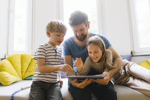 Son and daughter using tablet PC with father at home - JOSEF17123