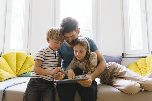 Father sharing tablet PC with son and daughter at home - JOSEF17124