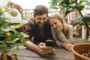 Vater teilt Smartphone mit Tochter auf dem Balkon - JOSEF17158