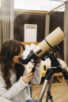Junge Frau schaut durch ein Teleskop in einer Kuppel - JJF00093