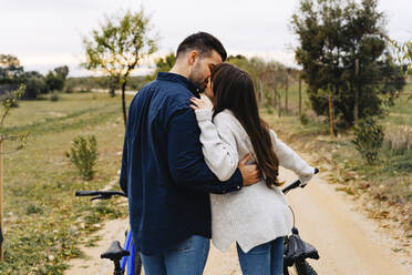 Romantic couple with bicycles kissing on dirt road - JJF00113