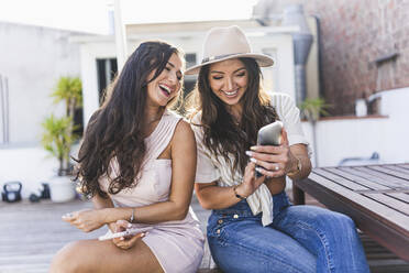 Happy friends using smart phone on rooftop - JJF00150