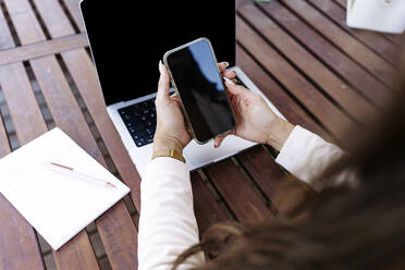 Freelancer using smart phone at table - JJF00176