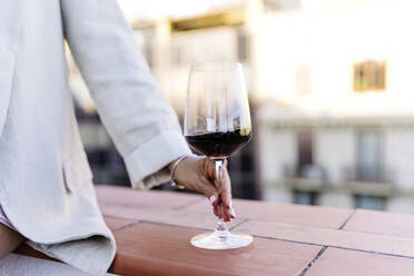 Woman with wineglass leaning on wall - JJF00194