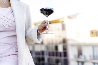 Woman holding glass of red wine - JJF00195