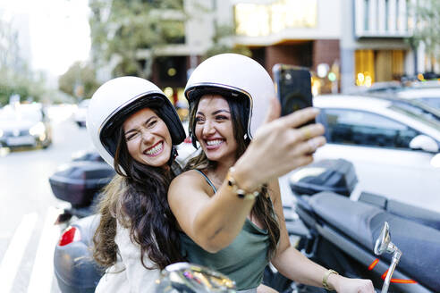 Fröhliche Frau mit Helm, die ein Selfie mit ihrem Smartphone macht - JJF00215