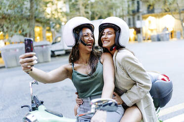 Glückliche Frau mit Helm, die ein Selfie mit ihrem Mobiltelefon macht - JJF00216
