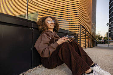 Nachdenkliche junge Frau mit Tablet-PC auf dem Fußweg sitzend - JCCMF09435