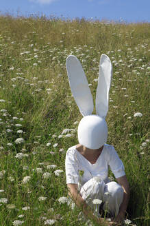 Frau mit Kaninchenmaske hockt im Feld - PSTF01027