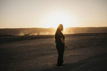 Junge Frau, die bei Sonnenuntergang auf einem Feldweg läuft - LHPF01468