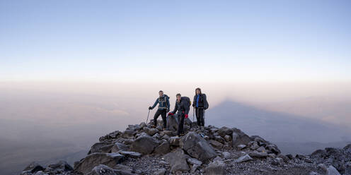 Friends standing on mountain in front of sky at sunset - ALRF02001