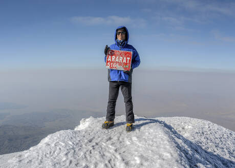 Lächelnder Wanderer mit Schild auf dem Gipfel des Mt. Ararat an einem sonnigen Tag - ALRF02006