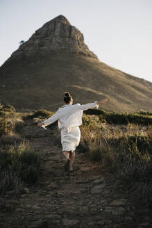 Frau läuft bei Sonnenuntergang auf den Berg Lion's Head zu - LHPF01473