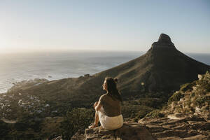 Woman admiring sea by Lion's Head Mountain at sunset - LHPF01485