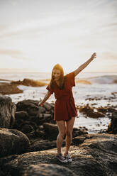 Young woman dancing on rock at beach - LHPF01490