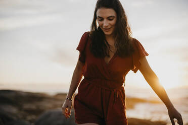 Young woman walking in front of sky at sunset - LHPF01491