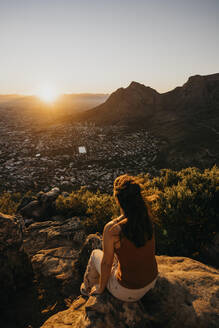 Frau sitzt auf einem Felsen und blickt vom Lion's Head Mountain auf das Stadtbild - LHPF01509