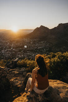 Woman sitting on rock looking at cityscape from Lion's Head Mountain - LHPF01509
