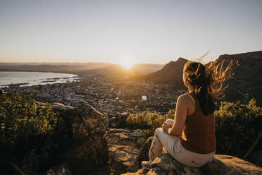 Frau auf einem Felsen mit Blick auf das Stadtbild vom Lion's Head Mountain bei Sonnenaufgang - LHPF01510