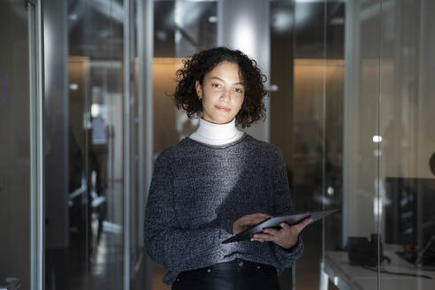 Junge Geschäftsfrau mit Laptop im Korridor am Arbeitsplatz - MCVF01052