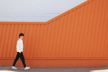 Man walking on footpath by wall - LMCF00148