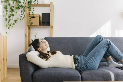 Junge Frau entspannt sich auf dem Sofa zu Hause - XLGF03243