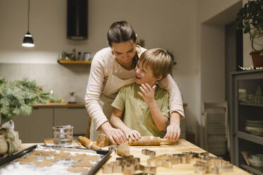 Glücklicher Sohn beim Backen von Ingwerkeksen mit Mutter in der Küche - VBUF00257