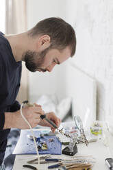 Techniker, der in einer Werkstatt Geräte mit einem Lötkolben repariert - ONAF00411