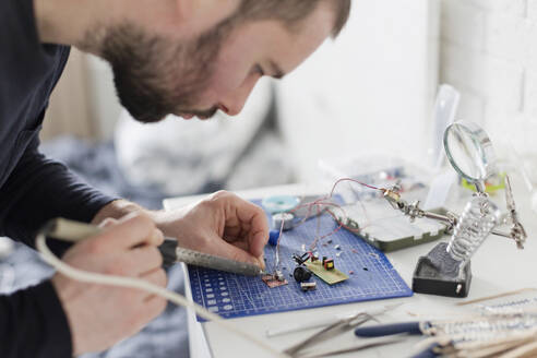 Engineer soldering circuit board at workshop - ONAF00412