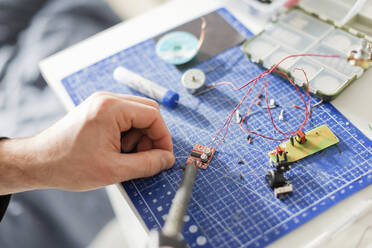 Hand of technician soldering circuit board at workshop - ONAF00413