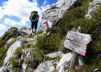 Ältere Frau beim Wandern auf einem Berg unter bewölktem Himmel - ALRF02014