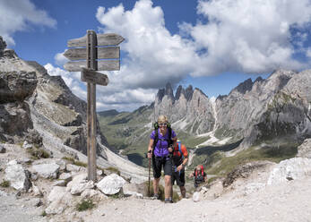 Women and man hiking under cloudy sky at Col da la Pieres, Dolomites, Italy - ALRF02037