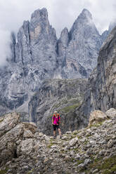 Senior woman standing in front of mountain at Passo di Venegiota, Dolomites, Italy - ALRF02069