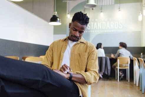 Businessman using smart watch sitting at office - ASGF03306