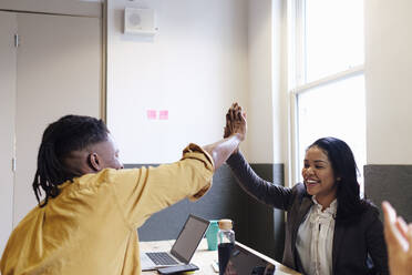 Businesswoman giving high-five to colleague at workplace - ASGF03373