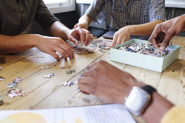 Geschäftskollegen beim Puzzeln am Schreibtisch im Büro - ASGF03379