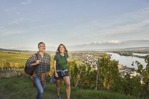 Glückliche Touristen wandern durch Weinberge unter dem Himmel - RORF03360