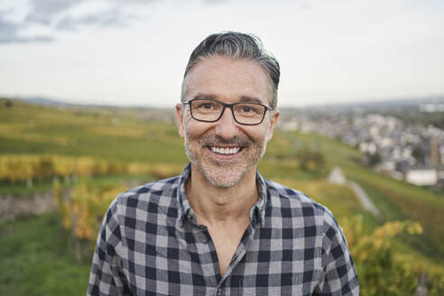 Happy mature man wearing eyeglasses in front of sky - RORF03386