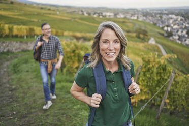 Happy woman with man in background walking on hill - RORF03392