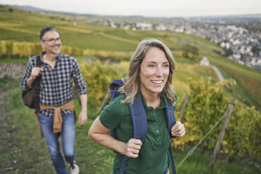 Thoughtful woman wearing backpack with man walking in background - RORF03393