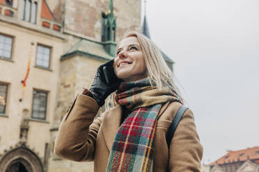 Smiling woman talking on smart phone in city - VSNF00440