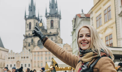 Smiling woman pointing at building in city - VSNF00442