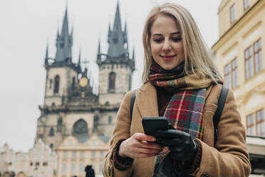 Lächelnde Frau, die über ihr Smartphone im Internet surft - VSNF00444