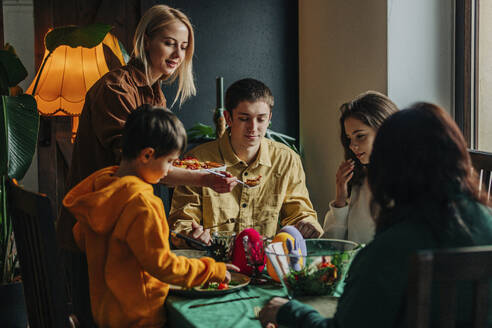 Happy family having Easter dinner at table in home - VSNF00464