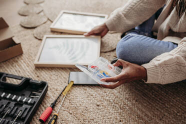 Woman making DIY picture frames sitting at home - EBBF08001